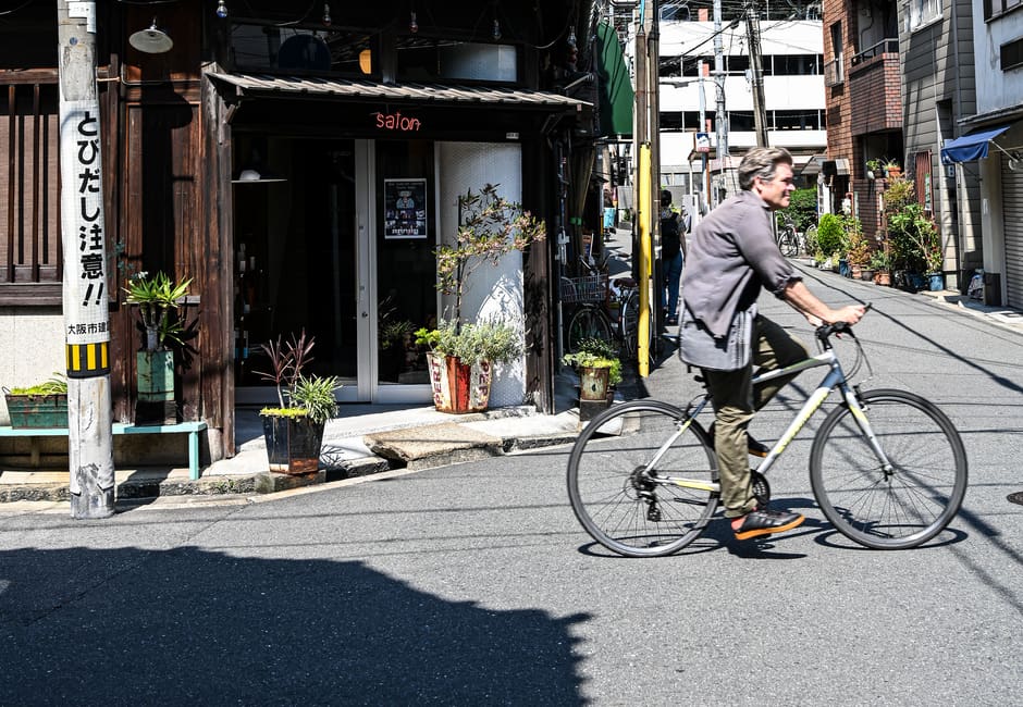 Narrow Nakazakicho street with an old wooden shopfront and a cyclist in Osaka