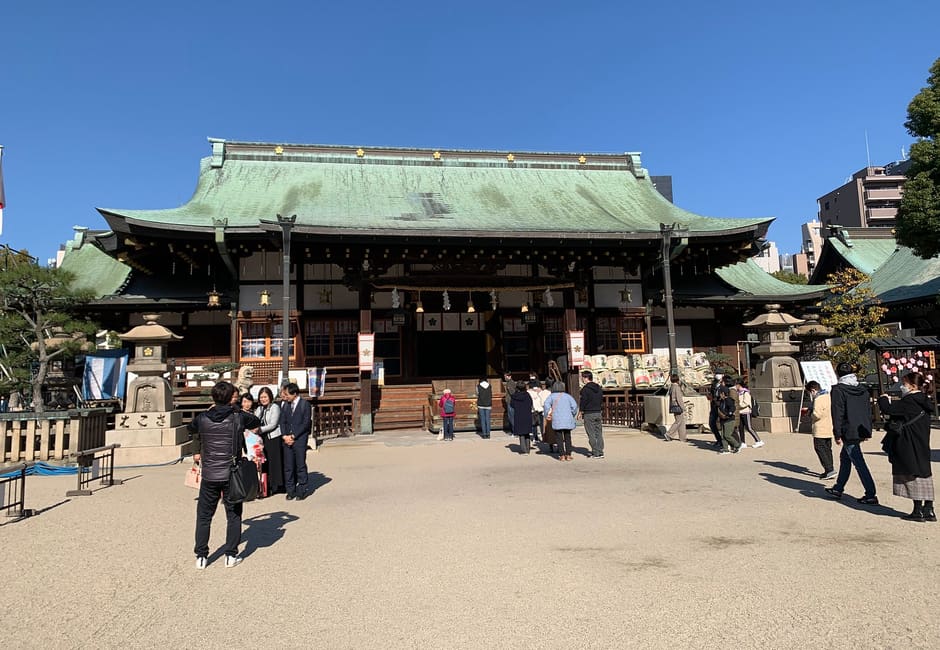 Main hall of Osaka Tenmangu with its green copper roof and visitors in the courtyard