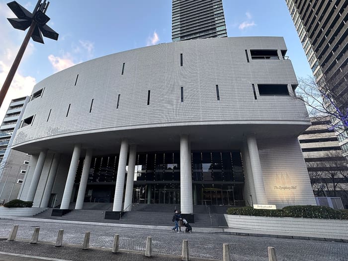 White curved facade and tall columns of The Symphony Hall in Osaka on a sunny day