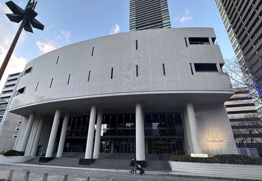 White curved facade and tall columns of The Symphony Hall in Osaka on a sunny day